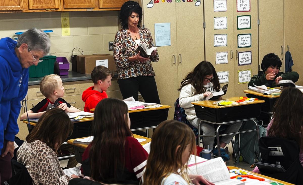 Lexa Speidel encouraging the third graders to find bits of interest in their new dictionary, like the longest word with 1,909 letters. Click to read article