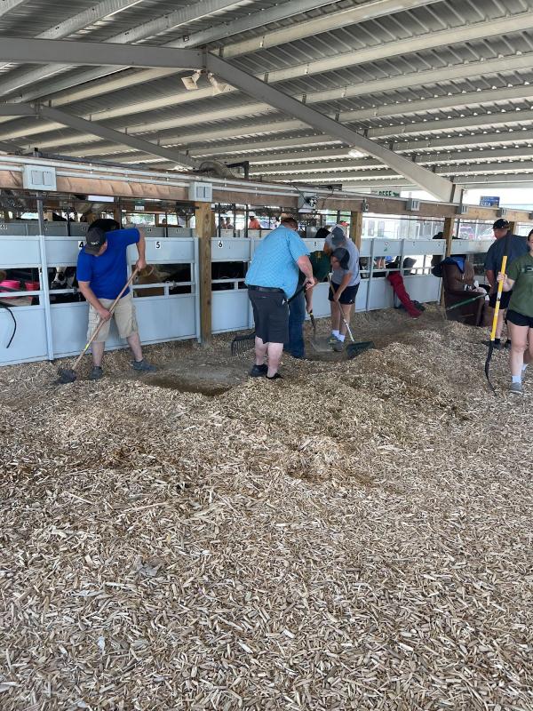 FFA Members and Alumni helping clean up wood chips in the FFA Barn.